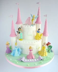 there is a white cake with princesses on it and the castle in the background