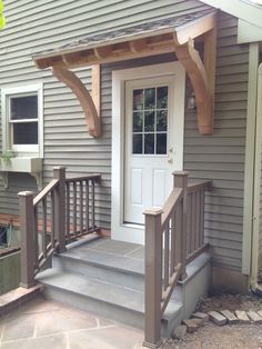 a porch with steps leading up to the front door and entry way that has a pergolan roof