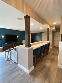 an open concept living room and kitchen area with bar stools in the center, blue accent wall