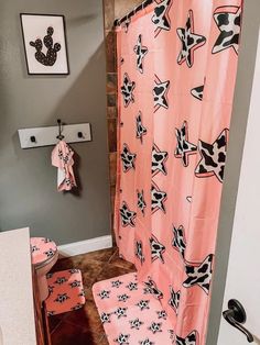 a pink shower curtain with black and white designs on it next to a toilet in a bathroom