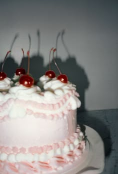 a pink cake with white frosting and cherries on top