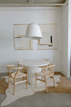 a white table and chairs in a room with artwork on the wall behind it,