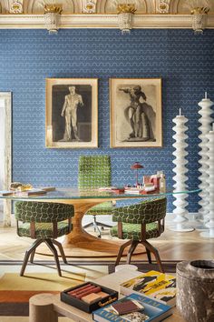 a living room with blue walls and pictures on the wall, two green chairs in front of a glass table