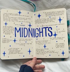 someone is holding an open book with the words midnights written in blue on it