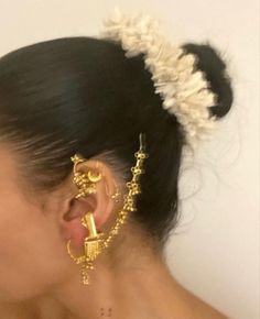 a close up of a person wearing gold ear rings and earrings with pearls on them