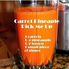 carrot pineapple pick me up recipe in a glass on the counter top next to an orange juicer