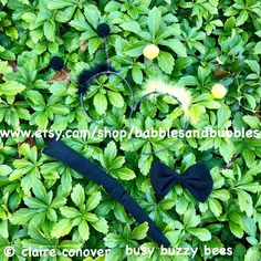 there is a black bow tie and other items in the bushes, with leaves around it