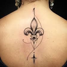 the back of a woman's neck with a fleur de lis tattoo on it