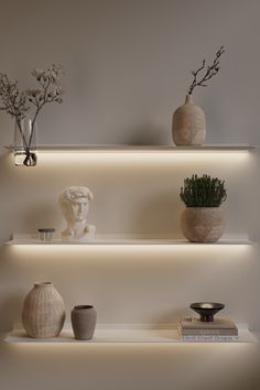 three white shelves with vases and plants on them