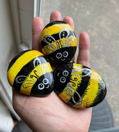 three painted rocks in the shape of bums are held up by someone's hand