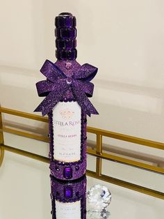 a purple bottle with a bow on it sitting on a table next to a crystal object