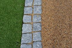 two different colored stones are next to each other on the grass and dirt area in front of them