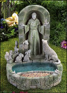 a statue of jesus surrounded by dogs in a garden