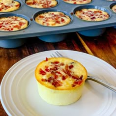 a muffin on a plate with a fork and cupcake tins in the background