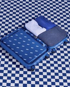 two pieces of luggage sitting on top of a checkered floor with blue and white tiles