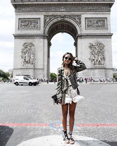 a woman standing in front of the arc de triumph