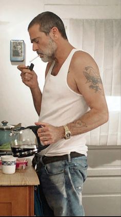 a man standing in a kitchen preparing food on top of a wooden counter next to a stove