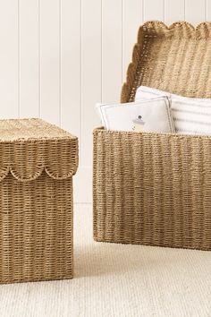 two wicker storage baskets sitting next to each other on the floor in front of a white wall