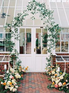 an outdoor wedding ceremony with flowers and greenery on the front door, surrounded by brick walkway