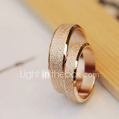 two gold wedding rings sitting on top of each other