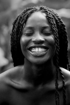 a woman with dreadlocks smiling and looking at the camera in black and white