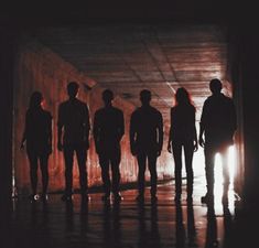 silhouettes of people standing in a dark tunnel