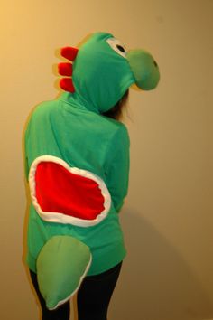 a person in a green dinosaur costume standing next to a wall