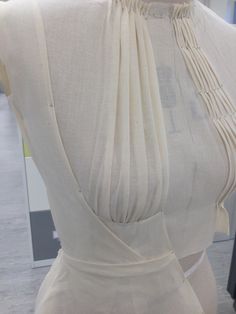 a mannequin wearing a white dress with an open back and tassels