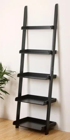 a black ladder shelf sitting on top of a wooden floor next to a potted plant