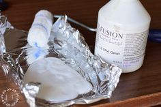 a bottle of lotion sitting on top of aluminum foil next to a tube of toothpaste