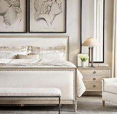 a white bed sitting in a bedroom next to two framed pictures