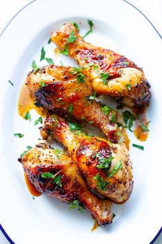 two pieces of chicken on a white plate with garnishes and parsley