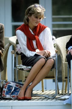 a woman sitting in a chair wearing a red scarf