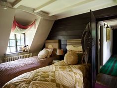 two twin beds in a bedroom with wooden floors and white walls, one has a green rug on the floor