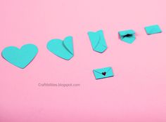 several pieces of blue paper with hearts cut out of them on a pink background,