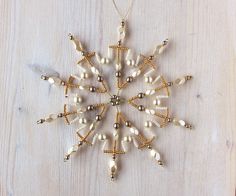 a snowflake ornament made out of beads on a wooden table top