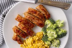 meat, macaroni and broccoli on a white plate with a knife