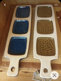 two pans with blue and brown food in them on a wooden table next to utensils