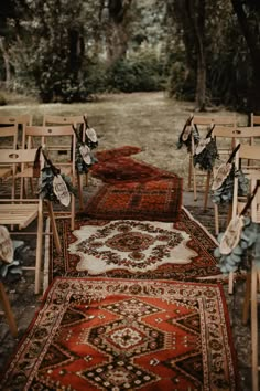 rows of wooden chairs and rugs lined up on the ground in front of trees