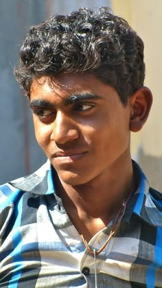 a close up of a person wearing a plaid shirt and looking at the camera with a serious look on his face