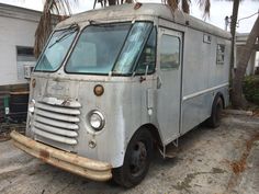 an old silver truck parked in front of a palm tree on the side of the road