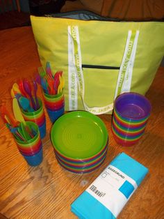 there are many colorful dishes and cups on the table with a tote bag in the background