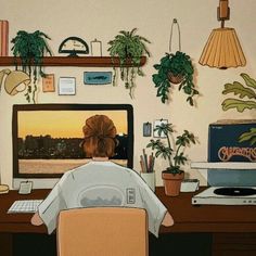 a person sitting at a desk in front of a computer with plants on the wall