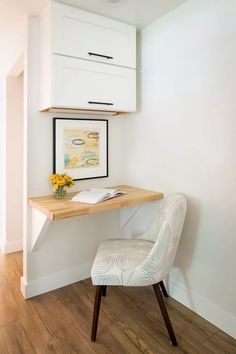 a white chair sitting under a desk with a book and flowers on top of it