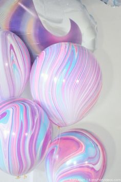 marbled balloons with pink, blue and white swirls are on the table next to each other