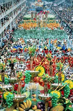 a large group of people standing in the middle of a street filled with lots of fruit