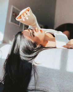 a woman laying on top of a bed next to a hair dryer in her hand