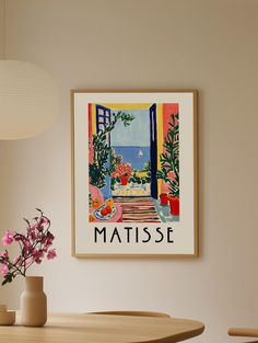 there is a vase with pink flowers on the table next to a poster that says matisse