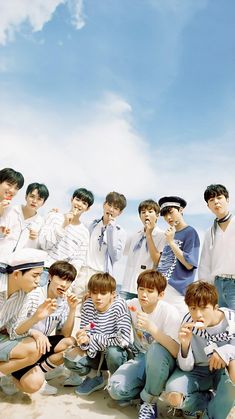 a group of young men sitting next to each other on top of a sandy beach