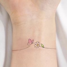 a small tattoo on the wrist of a woman's left arm with flowers and leaves